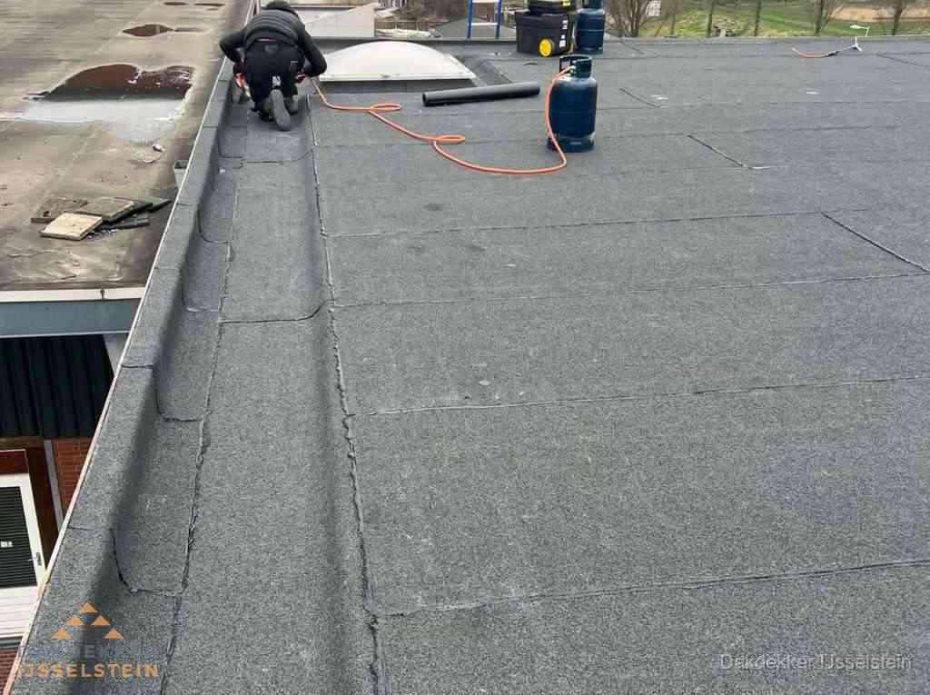 Dakdekker repareert bitumen dakbedekking op groot plat dak in IJsselstein